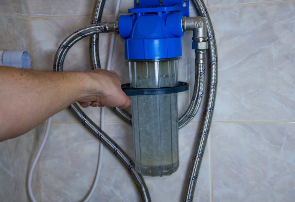 A person attaching a water softener to a wall.