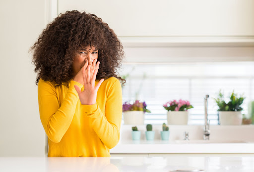 A Woman Holding Her Nose Because Of A Bad Smell In The Kitchen.