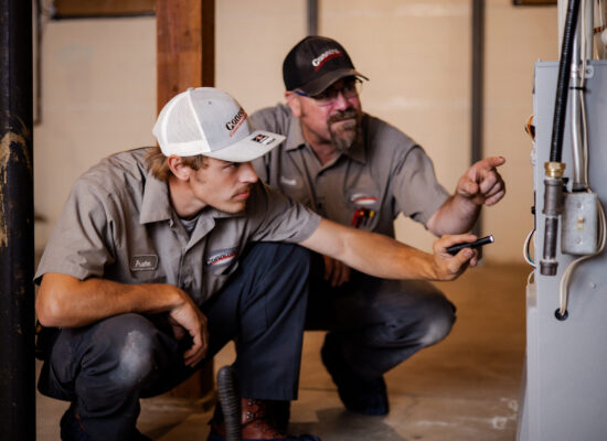 Two Connors Plumbing & Heating technicians inspecting a furnace.