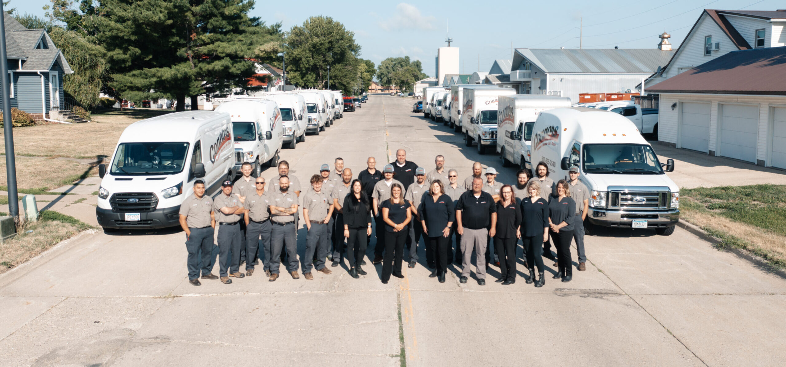 The Connors Plumbing & Heating team standing outside with company vehicles.