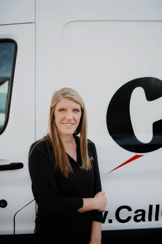 A friendly Connors team member with blonde hair stands by a branded service van, reflecting our welcoming company spirit.