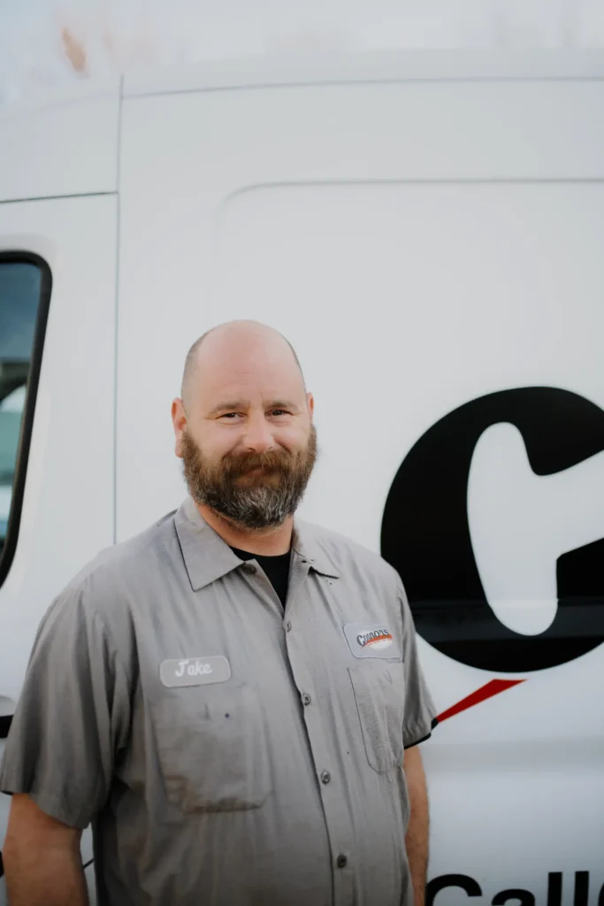 A bearded Connors team member in a gray work shirt stands by a white service van with partial "about us" lettering visible.