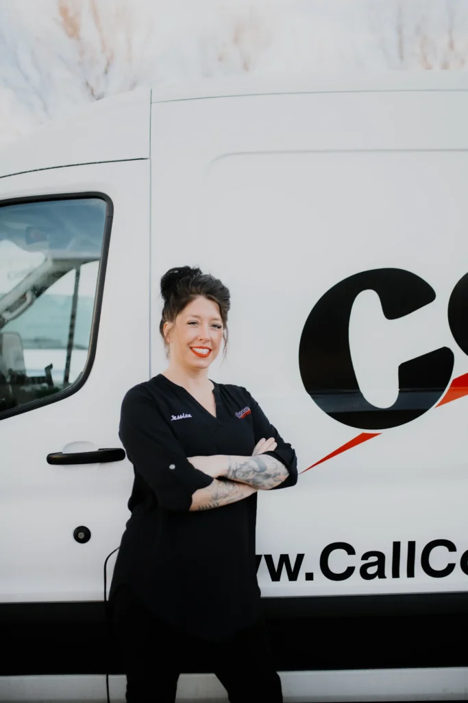 A team member with dark hair and tattoos stands confidently by a Connors service van, ready to assist our valued customers.
