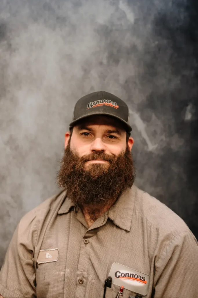 A friendly Connors team member with a beard, wearing a branded cap and uniform, poses proudly for our About Us page portrait.