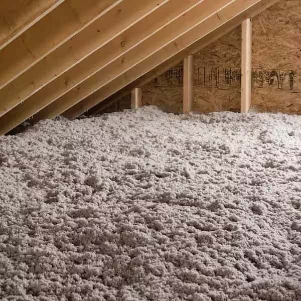 A view of loose-fill attic insulation covering floor joists between wooden rafters, illustrating the quality work provided by the Connors Plumbing, Heating, Air, & Electrical team.